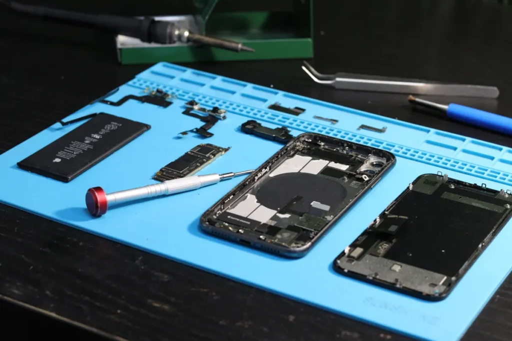 Smartphone parts and repair tools laid out on a mat